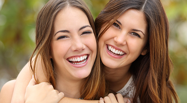Deux jeunes femmes riant sur un fond vert - © Shutterstock http://www.shutterstock.com/fr/pic-233369242/stock-photo-two-women-friends-laughing-with-a-perfect-white-teeth-with-a-green-background.html